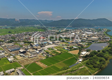 從空中俯瞰宮崎縣延岡市的城市、稻田、太陽能板和海灣地區。 140009654