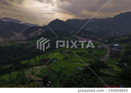 An aerial photograph of the terraced rice fields and red bridge in Hinokage Town, Kumamoto Prefecture, taken at dusk. An aerial photograph of the terraced rice fields and red bridge in Hinokage Town, Kumamoto Prefecture, taken at dusk. 140009693