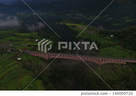 從空中俯瞰熊本縣日之影町一座籠罩在霧氣中的粉紅色桁架橋。 從空中俯瞰熊本縣日之影町一座籠罩在霧氣中的粉紅色桁架橋。 140009720