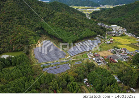 An aerial photograph overlooking a solar power plant surrounded by forests in Taka District, Hyogo Prefecture. An aerial photograph overlooking a solar power plant surrounded by forests in Taka District, Hyogo Prefecture. 140010252