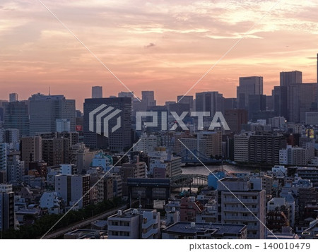 一張空拍照片，展現了黃昏時分東京江東區隅田川沿岸的城市景象。 140010479