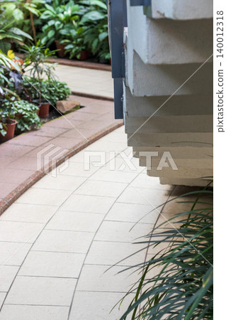 An indoor architectural walkway or botanical garden path looking alongside a heavy concrete staircase structure An indoor architectural walkway or botanical garden path looking alongside a heavy concrete staircase structure 140012318