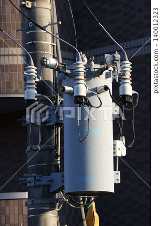 Close-up of a pole-mounted transformer and wiring installed on a utility pole. Close-up of a pole-mounted transformer and wiring installed on a utility pole. 140012323