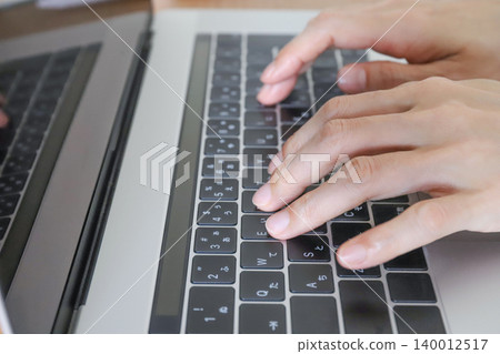 Hands typing on a laptop 140012517