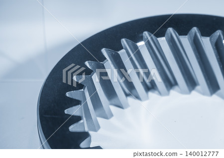 Close-up of high-precision inner bevel gear parts and mechanical teeth components in a blue-toned industrial scene. Close-up of high-precision inner bevel gear parts and mechanical teeth components in a blue-toned industrial scene. 140012777