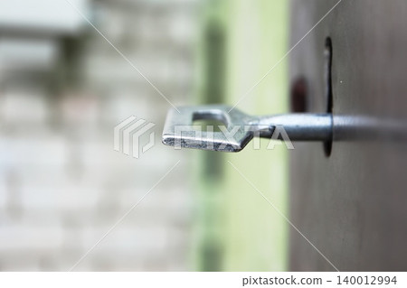 Garage Door Key in Lock Macro with Urban Bokeh Background, Weathered Industrial Security Hardware Detail Garage Door Key in Lock Macro with Urban Bokeh Background, Weathered Industrial Security Hardware Detail 140012994