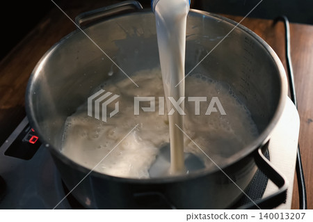 Pouring milk into the pan on scales. Pouring milk into the pan on scales. 140013207