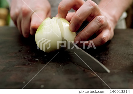 Cutting onions on a cutting board in kitchen. Cutting onions on a cutting board in kitchen. 140013214