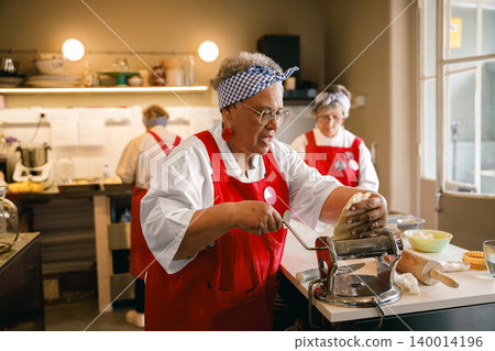Senior African American woman making pasta dough in a commercial kitchen Senior African American woman making pasta dough in a commercial kitchen 140014196