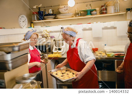Senior Caucasian and Black women baking fresh pastries in a commercial kitchen 140014332