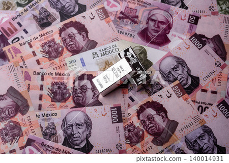 A silver bar, white metal against a backdrop of Mexican money, concept for the sales market A silver bar, white metal against a backdrop of Mexican money, concept for the sales market 140014931