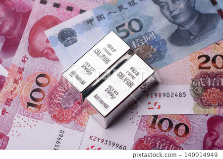 A silver bar, white metal against a backdrop of Chinese money, as a concept for the sales market A silver bar, white metal against a backdrop of Chinese money, as a concept for the sales market 140014949