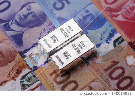 A silver bar, white metal against a backdrop of Canadian money, as a concept. A silver bar A silver bar, white metal against a backdrop of Canadian money, as a concept. A silver bar 140014981