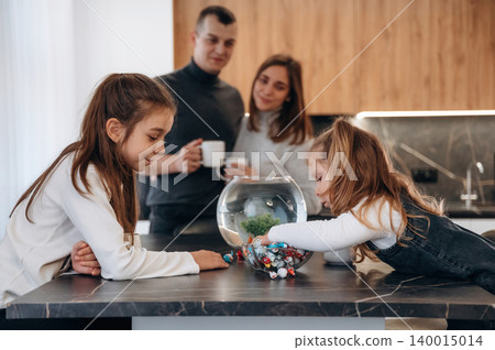 Family enjoying quality time in a modern kitchen, with children playing and exploring colorful toys near a fishbowl, creating a warm and inviting atmosphere Family enjoying quality time in a modern kitchen, with children playing and exploring colorful toys near a fishbowl, creating a warm and inviting atmosphere 140015014