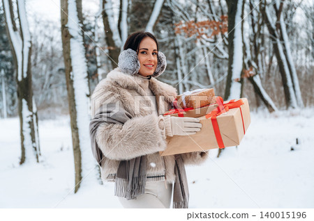 Woman in winter attire, holding wrapped gifts, walking through a snowy forest, surrounded by trees, showcasing festive spirit and holiday joy in a serene winter landscape Woman in winter attire, holding wrapped gifts, walking through a snowy forest, surrounded by trees, showcasing festive spirit and holiday joy in a serene winter landscape 140015196
