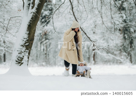 Woman in cozy winter attire joyfully pulling a sled with a child through a snowy forest, surrounded by frosted trees and a serene winter landscape, capturing the essence of family fun Woman in cozy winter attire joyfully pulling a sled with a child through a snowy forest, surrounded by frosted trees and a serene winter landscape, capturing the essence of family fun 140015605