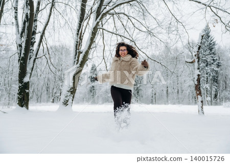 Young woman with curly hair, wearing a cozy fur jacket, joyfully running through a snowy landscape, surrounded by trees, capturing the essence of winter fun and happiness Young woman with curly hair, wearing a cozy fur jacket, joyfully running through a snowy landscape, surrounded by trees, capturing the essence of winter fun and happiness 140015726