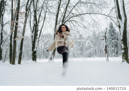Young woman in a cozy fur jacket joyfully running through a snowy forest, kicking up snowflakes, capturing the essence of winter fun and outdoor adventure 140015728