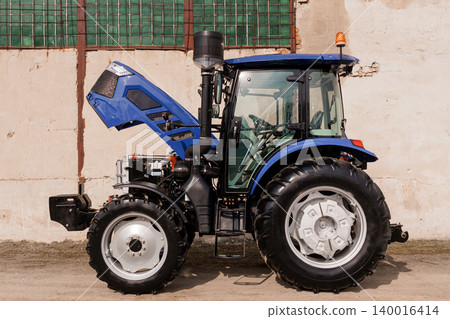 Blue Agricultural Tractor with Open Hood and Engine Exposed for Maintenance in Outdoor Setting 140016414