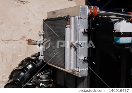 Close up of silver metal radiator and cooling system on black heavy machinery equipment Close up of silver metal radiator and cooling system on black heavy machinery equipment 140016417