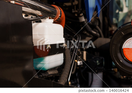 Close Up of Industrial Engine Component with White Fluid Reservoir and Black Metal Pipes Close Up of Industrial Engine Component with White Fluid Reservoir and Black Metal Pipes 140016424