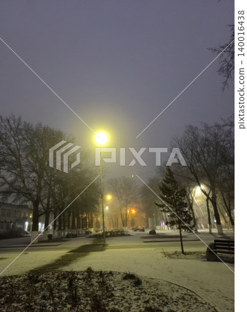 A peaceful winter night in a park, with snow covering the ground and warm street lamps casting soft shadows. The serene atmosphere invites quiet contemplation and leisurely strolls. A peaceful winter night in a park, with snow covering the ground and warm street lamps casting soft shadows. The serene atmosphere invites quiet contemplation and leisurely strolls. 140016438