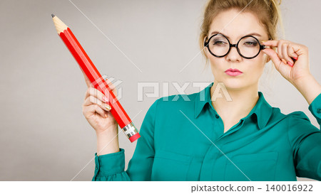 Woman confused thinking, big pencil in hand Woman confused thinking, big pencil in hand 140016922