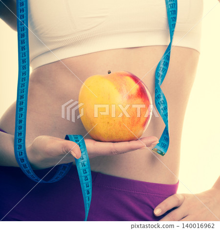 Diet healthy nutrition. Fit girl with measure tape, fruit apple. 140016962