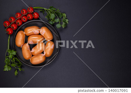 Raw sausages with cherry tomatoes and parsley on dark background 140017091