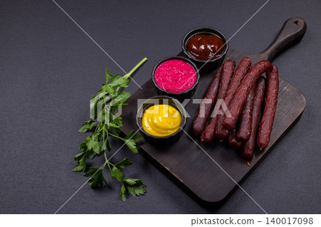 Smoked sausages and flavorful sauces on cutting board Smoked sausages and flavorful sauces on cutting board 140017098
