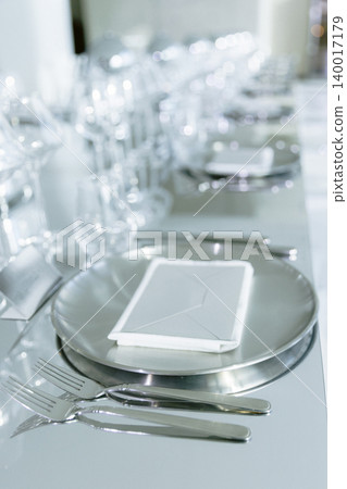 Restaurant table setup with white plates and crystal glasses 140017179