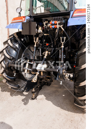Rear View of Blue Agricultural Tractor Showing Hydraulic Hitch and Large Rubber Tires on Concrete Rear View of Blue Agricultural Tractor Showing Hydraulic Hitch and Large Rubber Tires on Concrete 140017184