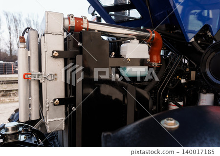 Close up of heavy duty tractor engine components and radiator with blue chassis and metal textures Close up of heavy duty tractor engine components and radiator with blue chassis and metal textures 140017185