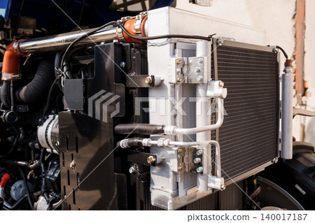 Close up of industrial radiator and engine components with metal pipes and silver cooling fins Close up of industrial radiator and engine components with metal pipes and silver cooling fins 140017187