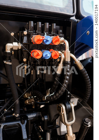 Close Up of Hydraulic Control Valves and Black Rubber Hoses on Blue Agricultural Tractor Machine Close Up of Hydraulic Control Valves and Black Rubber Hoses on Blue Agricultural Tractor Machine 140017194