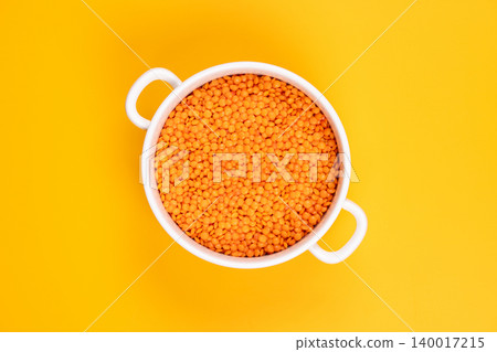 Red lentils in white bowl on yellow background Red lentils in white bowl on yellow background 140017215