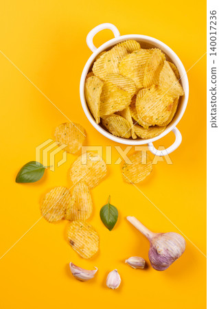 Wavy potato chips with garlic and fresh basil 140017236