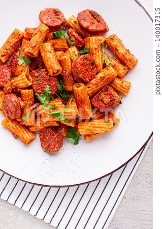 rigatoni pasta with spicy sausage, and rich tomato sauce served, on a white plate, homemade, 140017315
