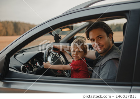 Father with his two-year-old son driving car in a field 140017815