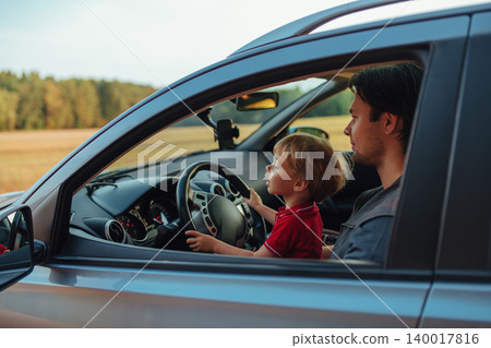 Father with his two year old son driving car in a field 140017816