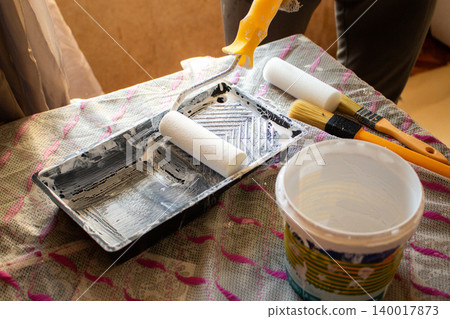 Paint roller and tray on table. Man is ready to do light makeover in his house. Home transformation. Creative home care concept Paint roller and tray on table. Man is ready to do light makeover in his house. Home transformation. Creative home care concept 140017873