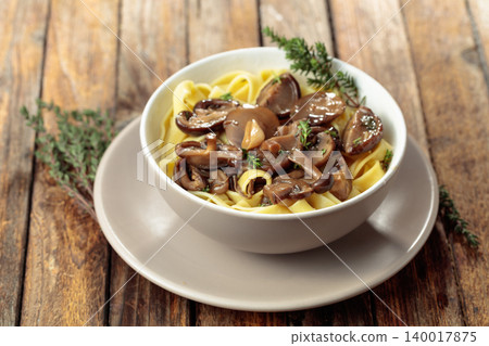 Noodles with mushrooms and thyme on a rustic wooden table. 140017875