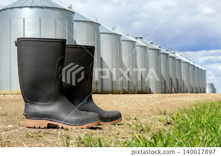 Gumboots in the rural farm road at the row of steel granaries. Gumboots in the rural farm road at the row of steel granaries. 140017897
