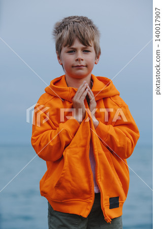 Portrait of boy standing on lake shore with folded arms Portrait of boy standing on lake shore with folded arms 140017907