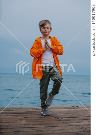 Boy standing in meditation pose at the edge of the sea Boy standing in meditation pose at the edge of the sea 140017908