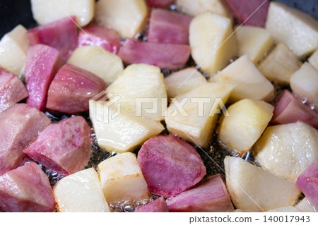 Close-up of diced pink and white potatoes in a frying pan. Close-up of diced pink and white potatoes in a frying pan. 140017943
