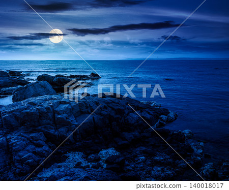 sea coast with stones and rocks at night. summer vacation background. full moon over seascape with rough terrain. fantasy relaxing at the sea. mysterious coast of bulgaria sea coast with stones and rocks at night. summer vacation background. full moon over seascape with rough terrain. fantasy relaxing at the sea. mysterious coast of bulgaria 140018017