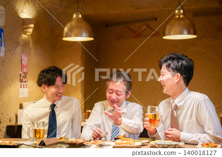 A male manager passionately speaking to younger employees at a company drinking party. A male manager passionately speaking to younger employees at a company drinking party. 140018127