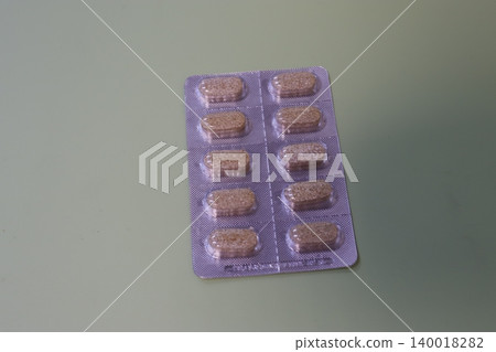 Blister Pack of Brown Pills on Green Background 140018282