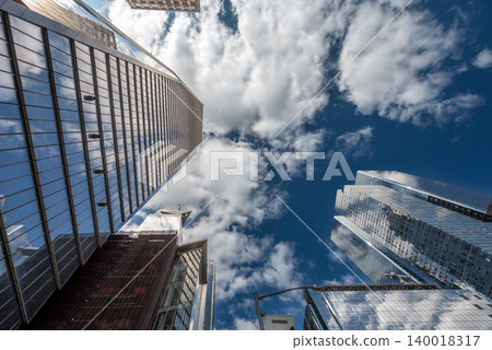 New york, usa august 20,2024. Modern glass skyscrapers soar toward a bright blue manhattan sky with white clouds, reflecting sunlight in a dynamic urban scene New york, usa august 20,2024. Modern glass skyscrapers soar toward a bright blue manhattan sky with white clouds, reflecting sunlight in a dynamic urban scene 140018317